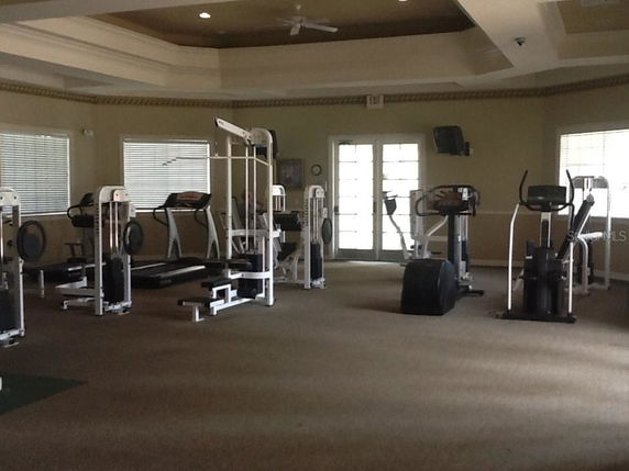 Room with gym equipment including treadmills and exercise machines.
