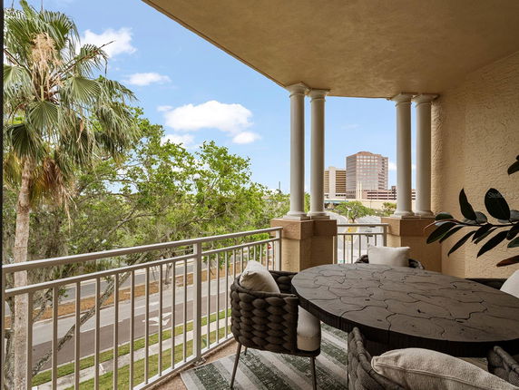 Balcony with a decorative table and outdoor seating offering a view of nearby buildings and trees.