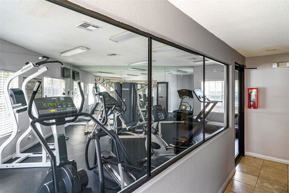 Indoor gym area with workout equipment and mirrored walls.
