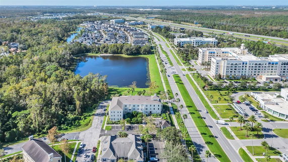 Aerial view of a residential area with a lake, roadways, and buildings.