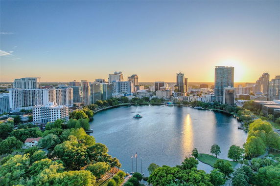 Panoramic view of a city skyline with a lake and surrounding buildings at sunset.