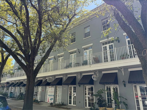 Front view of a multi-story building with a balcony and storefronts.