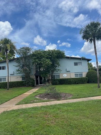 Front view of a two-story building with trees and bushes in front.