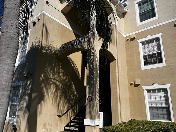 Front view of a multi-story beige building with white framed windows and an archway entrance.