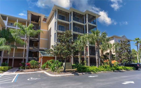 Front view of a multi-story building with balconies and palm trees.