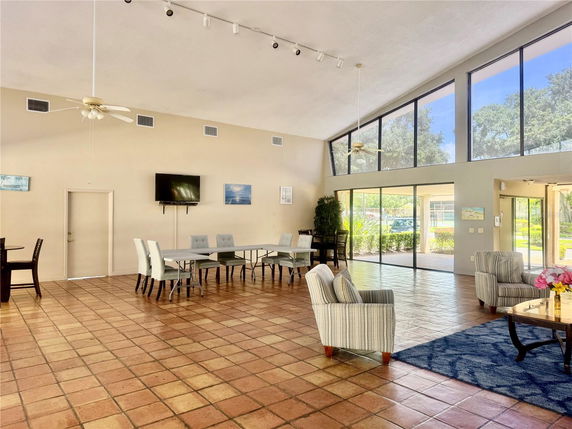 Interior view of a clubhouse with seating arrangements and large windows.