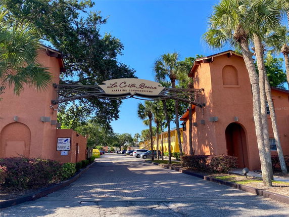 Front view of a condominium entrance with an archway and palm trees.