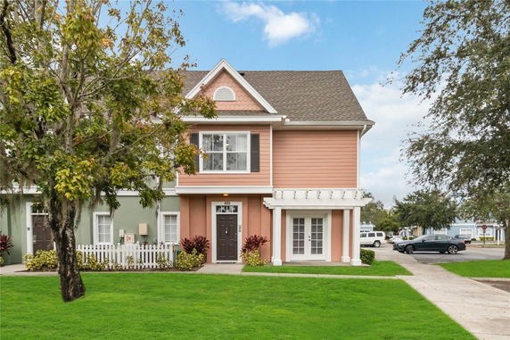 Front view of a colorful two-story house with a decorative porch and multiple windows.