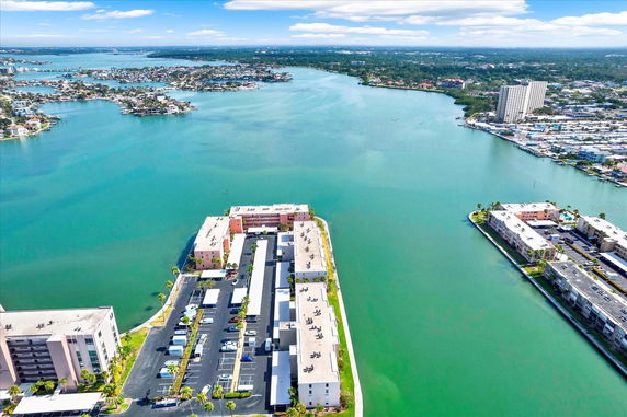 Aerial view of a waterway surrounded by multiple buildings, with a large expanse of water and distant landmasses.