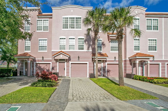 Front view of a multi-story townhouse building with garages and red-tile roofs.
