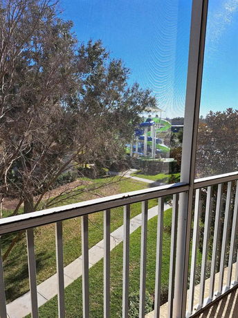 Balcony view with trees and a glimpse of a water slide in the distance.