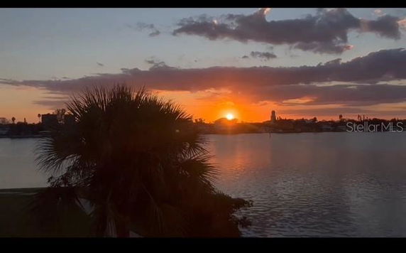 Panoramic view of a sunset over a body of water with a silhouetted landscape.