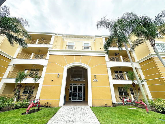 Front view of a multi-story building with balconies and an arched entrance.