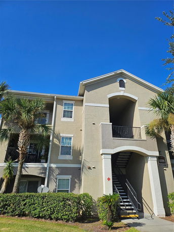 Front view of a multi-story residential building with balconies and external stairs.