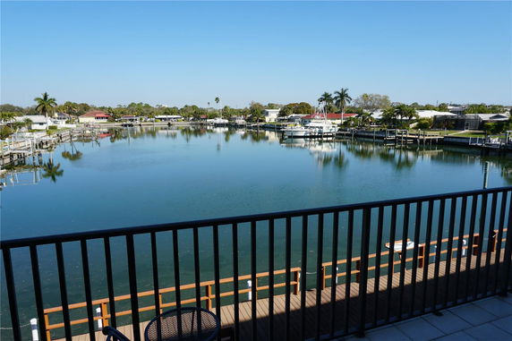 Wide angle view from a balcony overlooking a waterway with docks and boats, surrounded by residential houses.