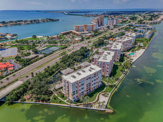 Aerial view of a residential complex surrounded by water and roads with visible buildings in the background.