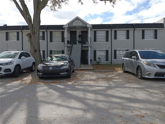 Front view of a two-story building with multiple units and parking area.