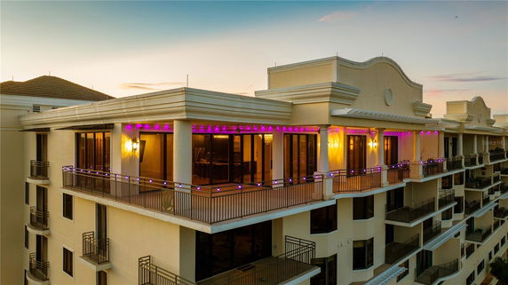 Front view of a multi-story building with balconies and decorative evening lighting.