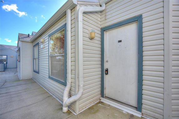 Exterior side view of a building with siding and a door labeled Unit 200.