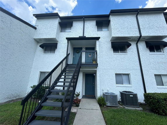 Front view of a multi-story building with two doors and an external staircase.