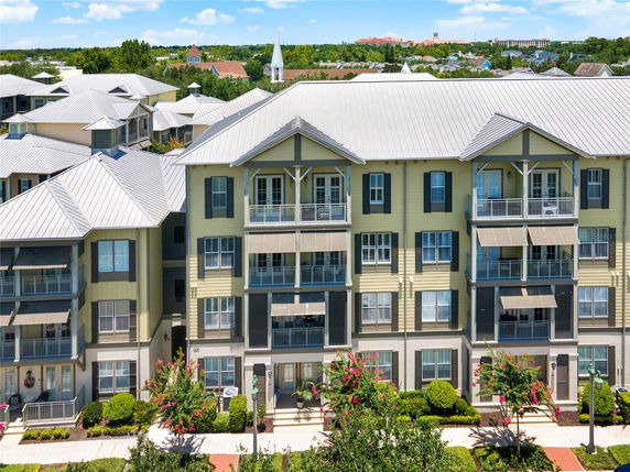 Front view of a multi-story building with balconies and a metal roof.