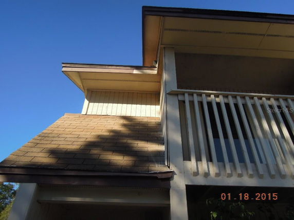 Close-up view of a house exterior showing a sloped roof and balcony.