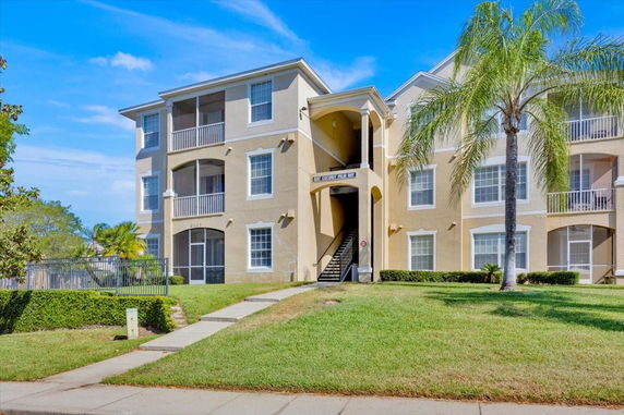Front view of a three-story apartment building with external staircases and balconies.
