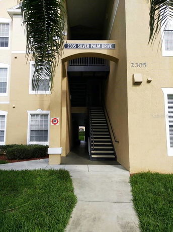 Front view of a multi-story apartment building with an open stairway entrance.