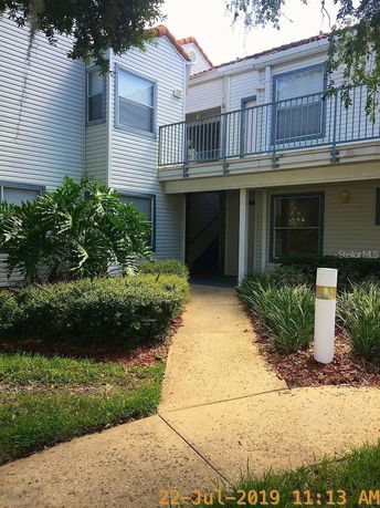 Front view of a two-story residential building with an outdoor staircase and upper-level balcony.