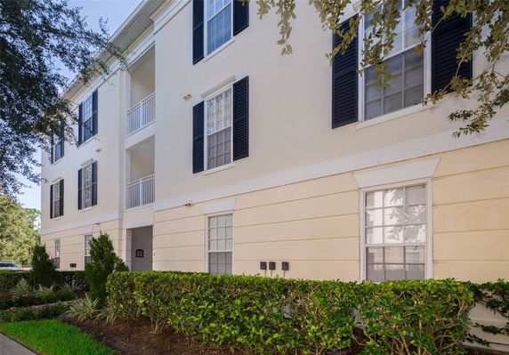 Front view of a multi-story building with black shutters and white railings.