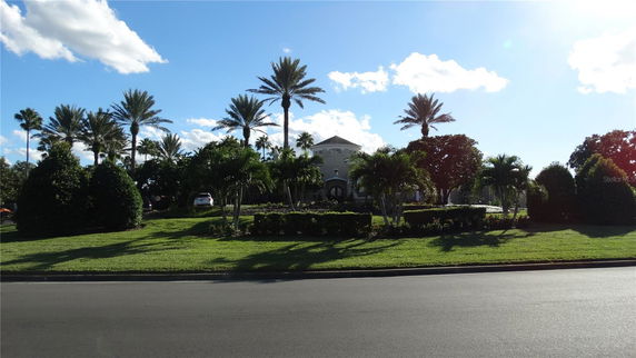 Front view of a house with a prominent entrance and surrounding palm trees.