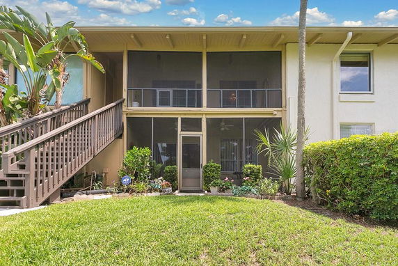 Front view of a two-story house with a staircase leading to a screened porch area.