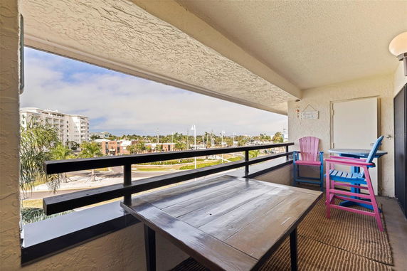 Balcony with colorful chairs and table overlooking a cityscape.