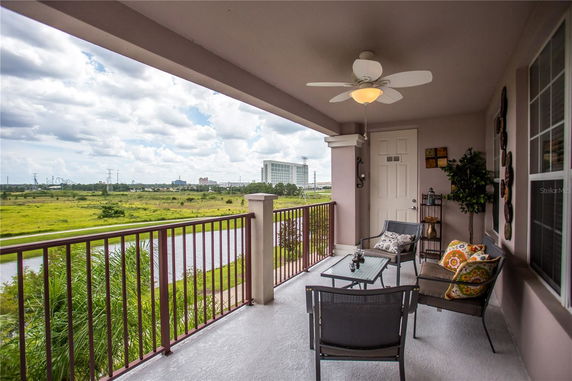 Balcony view with patio furniture overlooking a green landscape and a building in the distance.