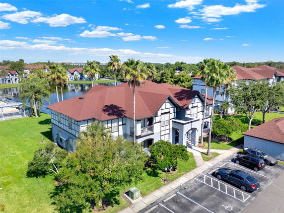 Front view of a two-story residential building with a red roof and parking area.