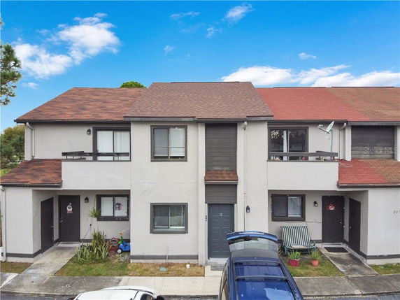 Front view of a townhouse complex with multiple units, featuring two stories and a red-tiled roof.