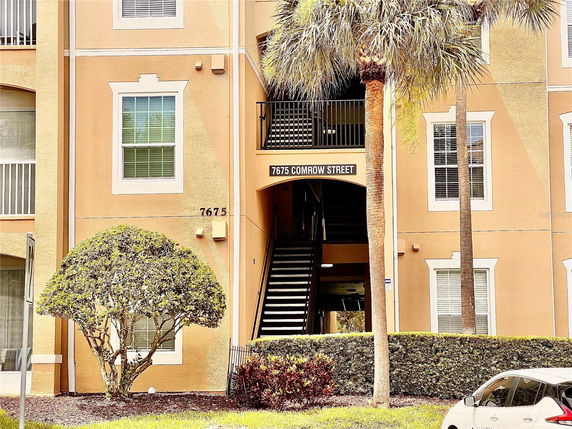 Front view of a multi-story building with an entrance staircase and address number displayed.