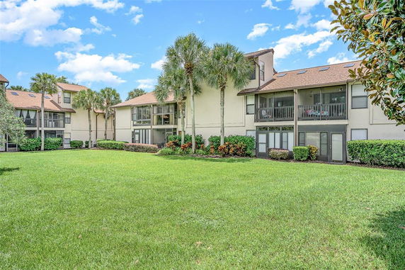 Rear view of a multi-story residential building with balconies and landscaping.