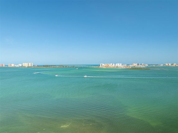 Panoramic view of a wide body of water with boats and distant buildings.