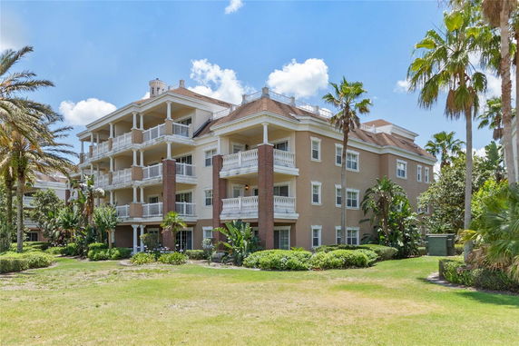 Front view of a multi-story residential building with balconies and palm trees.