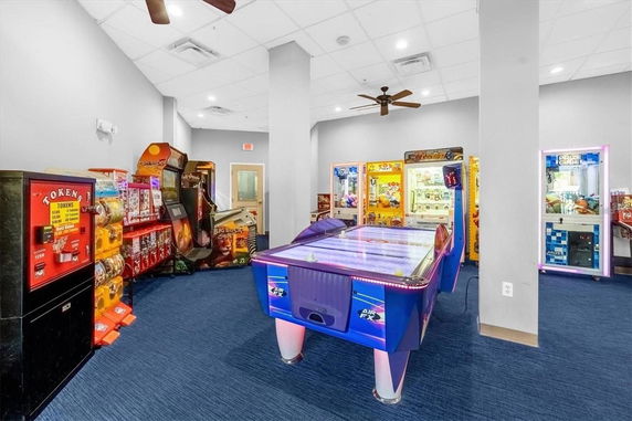 Indoor arcade room with various game machines and a token dispenser.