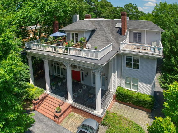 Front view of a large two-story house with a balcony and columns.