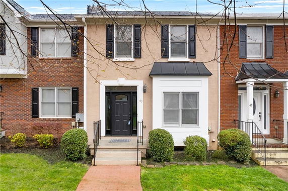 Front view of a townhouse with black shutters and a black front door.
