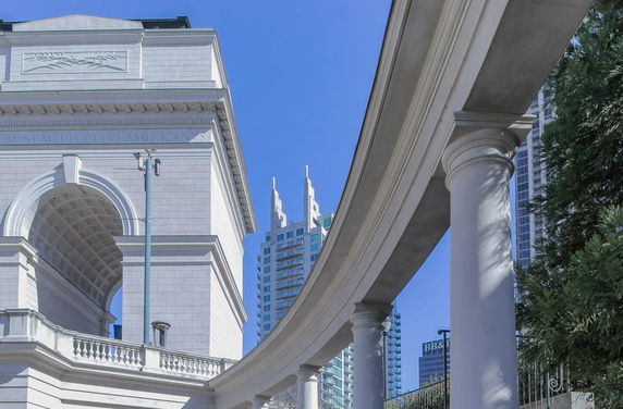 View of a building with classical architecture featuring an arch and columns.