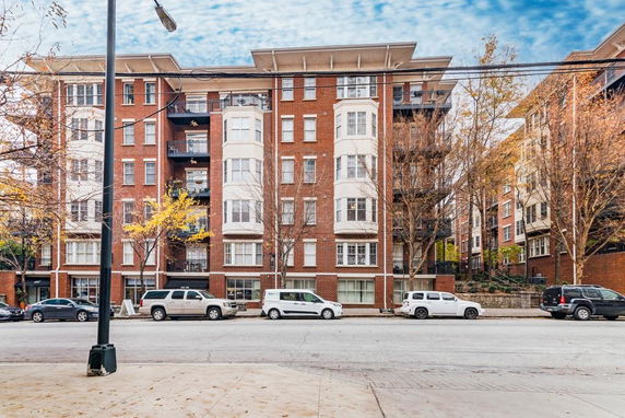 Front view of a multi-story brick apartment building with balconies.