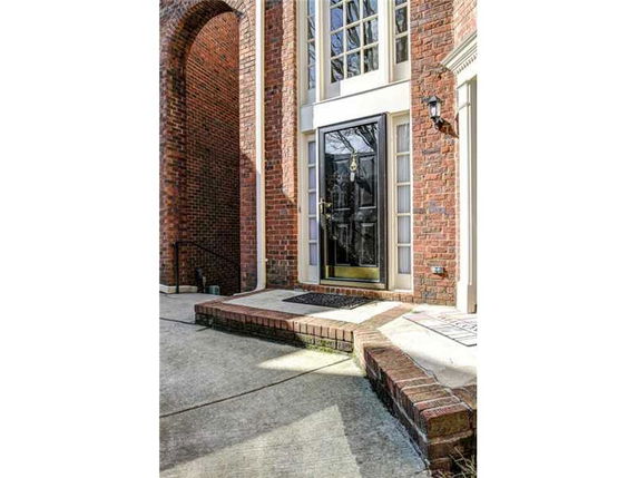 Front view of a brick house entrance with a black door and side windows.