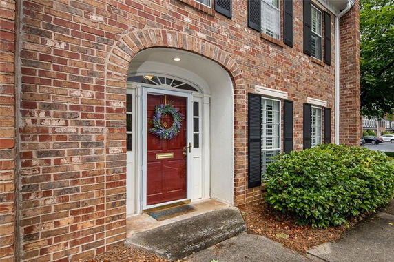 Front view of a house with a red door and brick exterior.
