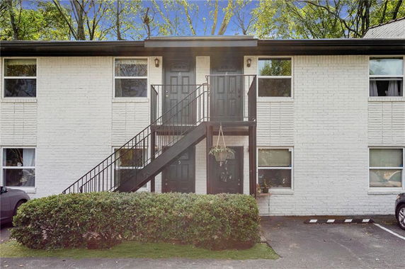 Front view of a two-story brick apartment building with exterior staircase leading to upper floor entrance.