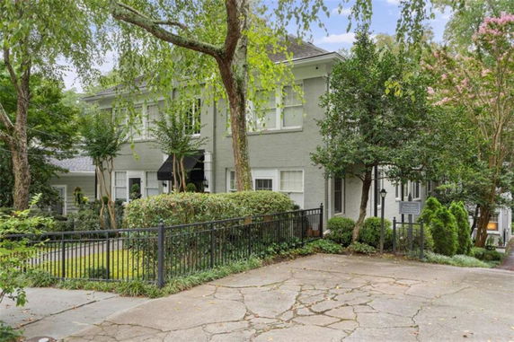 Front view of a two-story house with a driveway and wrought iron fence.