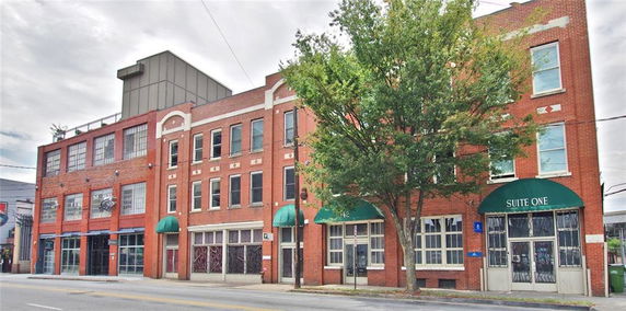 Front view of a series of connected multi-story brick buildings with green awnings.